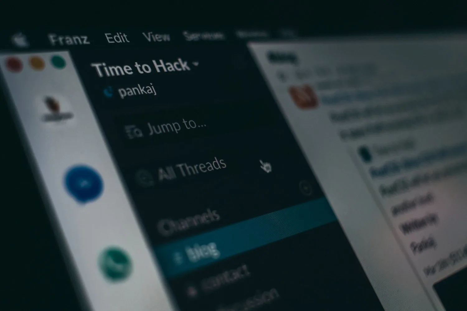 Close-up of a chat app on a screen showing a workspace called Time to Hack, with its threads and channels