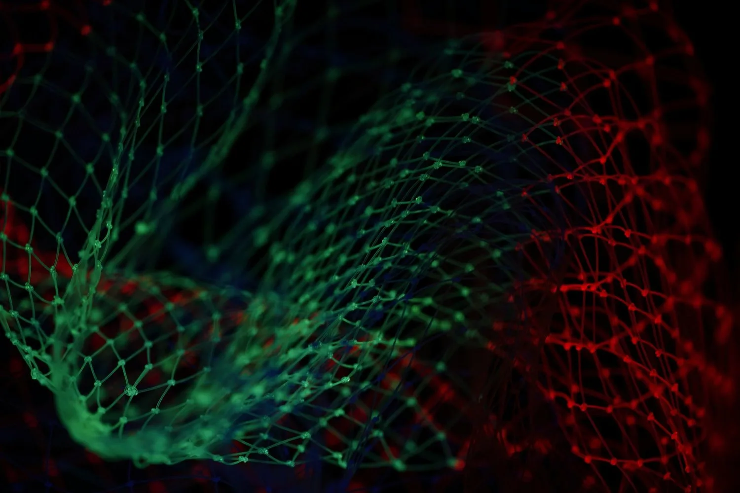 Abstract close-up of green and red illuminated mesh netting on a dark background