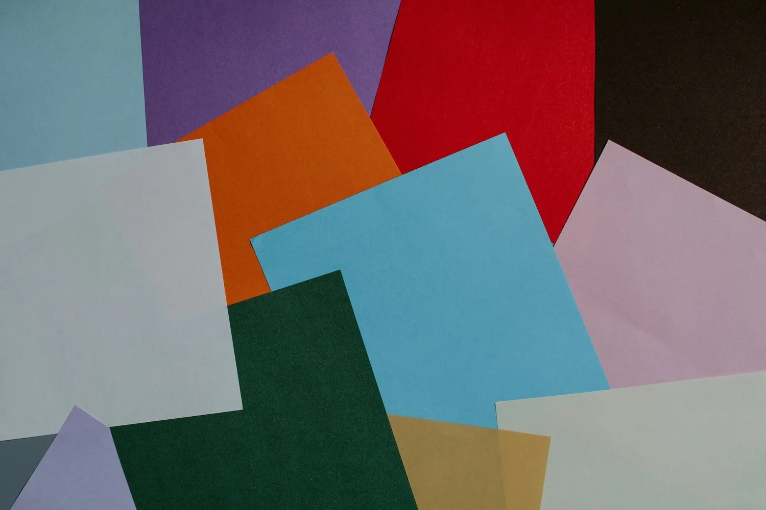 Overlapping sheets of coloured paper in blue, orange, red, green, pink and purple